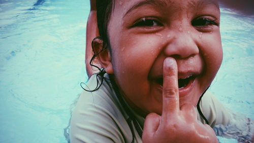 Close-up portrait of child with finger on lips in swimming pool