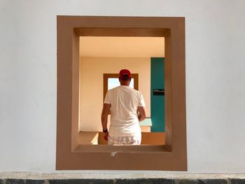 Rear view of man standing against door at home
