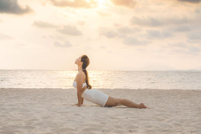 Full length of young woman doing yoga at beach