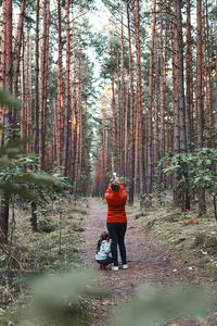 Mother and her little daughter walking in a forest during summer vacation trip. woman taking photos