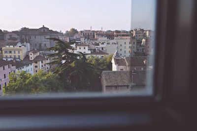 Buildings in city against sky seen through window