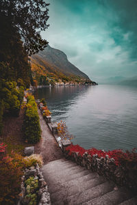 Garden next to a large body of water with mountains in the background during an overcast day