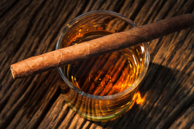 Close-up of cigar with whiskey glass on table