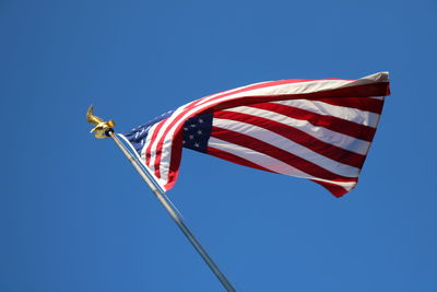 Low angle view of flag against clear blue sky