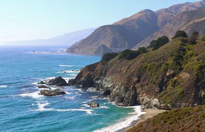 Scenic view of sea and mountains against clear sky