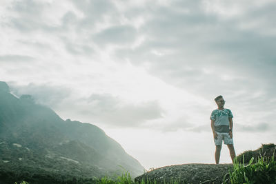 Rear view of man standing on mountain against sky