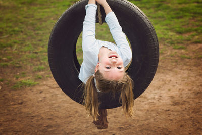 Portrait of cute girl playing with tire swing in playground