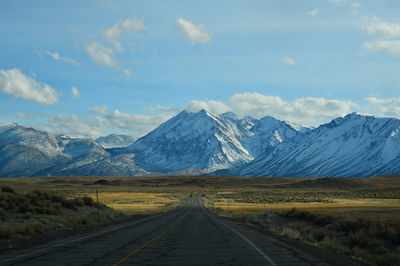 Road leading towards mountains against sky