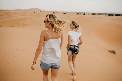 Rear view of woman walking on sand at beach