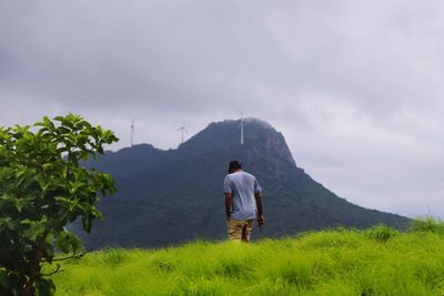 Rear view of man on field against sky