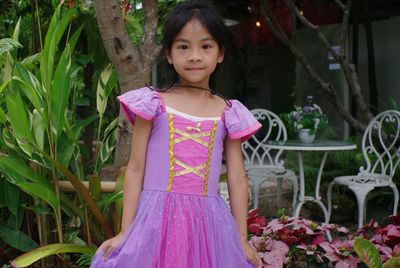 Portrait of girl standing against pink flowers