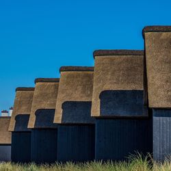 Low angle view of built structure on field against clear blue sky