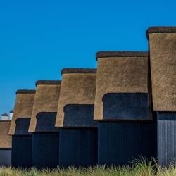 Low angle view of built structure on field against clear blue sky