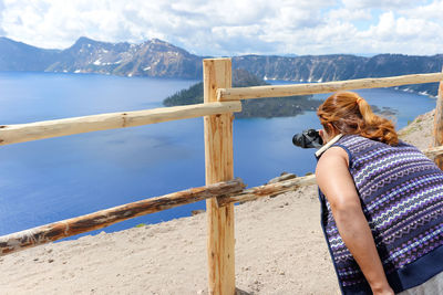 Rear view of woman looking at sea against mountain