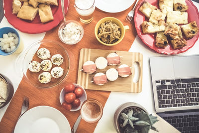 Table with many foods. aperitif at home with fresh finger food, tapas, beer and laptop computer. 