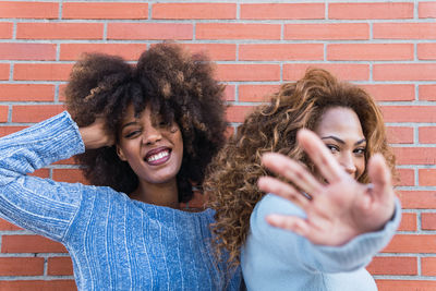 Smiling african american friends with long afro hair pulling hand towards camera