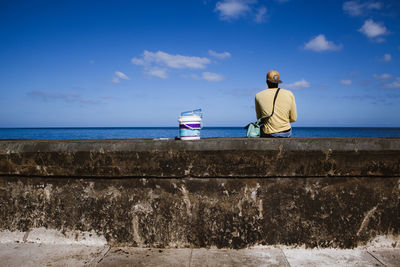 Woman standing on beach against blue sky