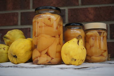 Close-up of fruits in jar on table against wall