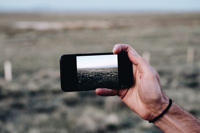 Midsection of man photographing with mobile phone