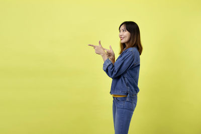 Side view of a smiling young woman against yellow background