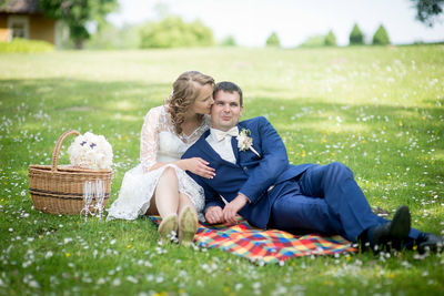 Newlywed couple sitting on picnic blanket at park