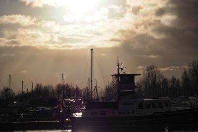 Sailboats moored at harbor against sky at sunset