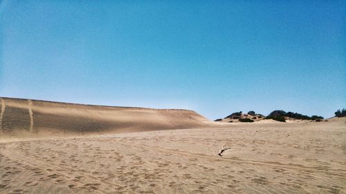 Scenic view of sand dunes against clear blue sky