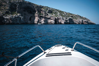 Sailboat sailing on rock by sea against sky