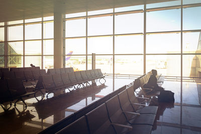 Stained glass window of the departure hall inside an airport with a girl sitting on chairs 