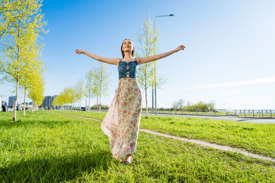 Attractive happy young woman long flowered dress flying her hair enjoying free