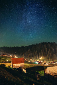 Built structure on illuminated field against sky at night