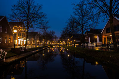 Canal amidst illuminated buildings against sky at night