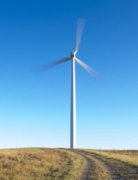 Wind turbine in motion against blue sky