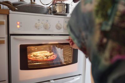 Woman checking food for eid al-fitr in oven