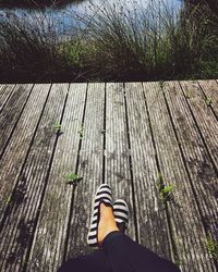 Low section of person on pier against lake