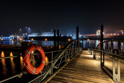 Life belt on boardwalk in illuminated city at night