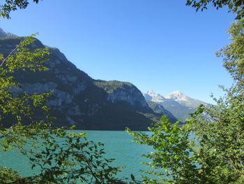 Scenic view of mountains and lake against clear blue sky