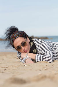 Portrait of woman in sunglasses lying at beach