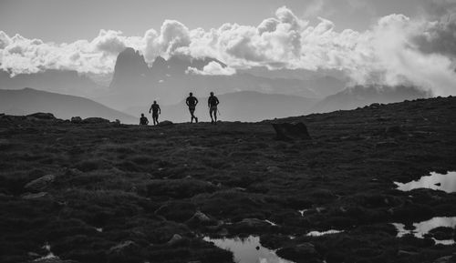 People on rocks by land against sky