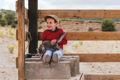 Cute smiling boy playing with cat outdoors