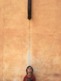 Boy looking up while standing against wall