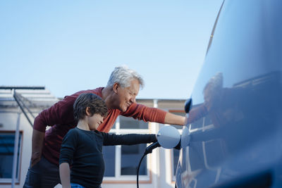 Grandfather and grandson charging electric car