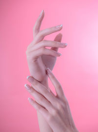 Close-up of woman hand over pink background