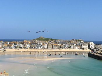 Houses by beach against clear blue sky