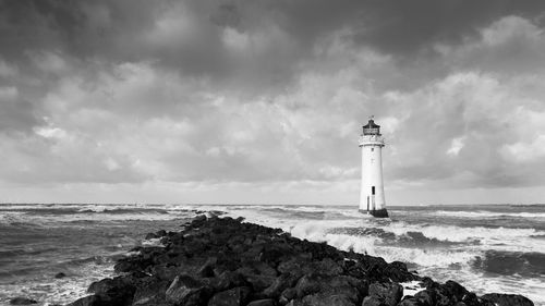 Lighthouse by sea against sky