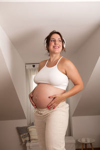 Beautiful pregnant woman, dancing and listening to music on the bed