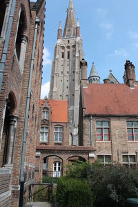 Low angle view of the historic church of our lady and medieval buildings in brugge. 