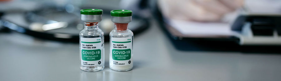 Two vials of coronavirus vaccine on a female doctor's table