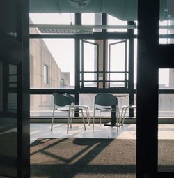 Empty chairs and table against window in office