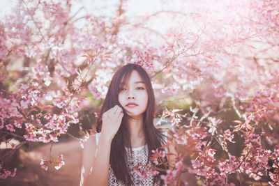 Young woman standing in front of cherry blossoms in park